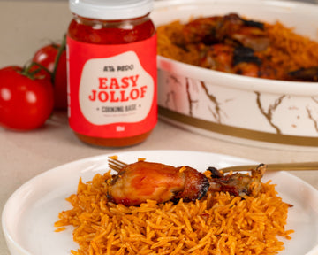 Jollof rice with chicken and a jar of 'Easy Jollof' seasoning on a table.