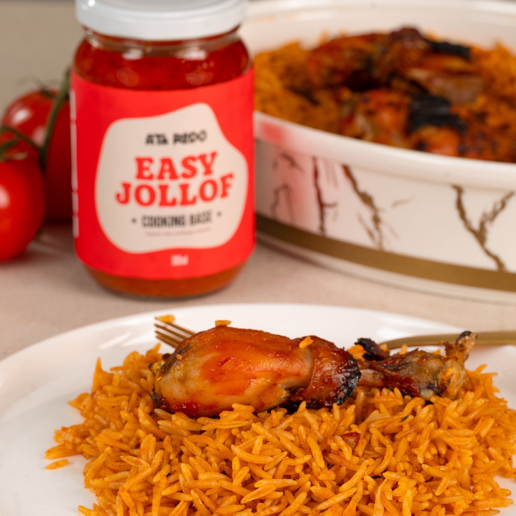 Jollof rice with chicken and a jar of 'Easy Jollof' seasoning on a table.